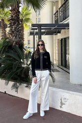 a lady in a black knit top and a pair of white wide leg pants